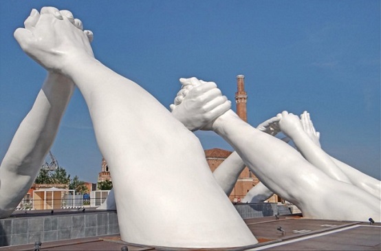 Skulptur, in der riesenhafte Arme sich über einem Kanal in Venedig die Hände reichen